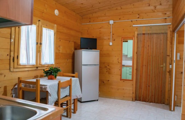 Interno in legno con tavolo apparecchiato e frigorifero.