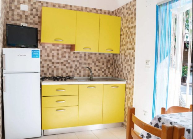 Cucina con mobili gialli, frigorifero e tavolo.