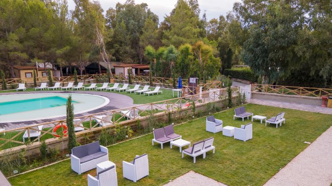 Spazio relax con sedie e tavoli vicino piscina.