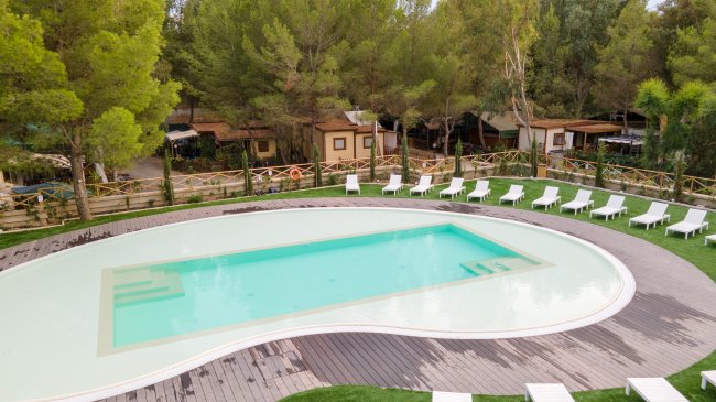 Piscina circondata da sdraio bianche.