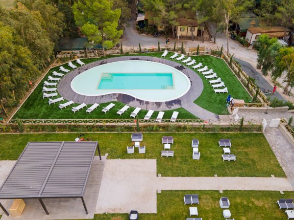 Piscina a forma di fagiolo con lettini intorno.