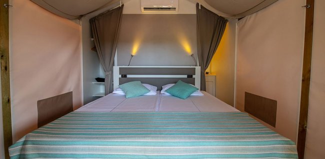 Letto matrimoniale con copriletto a righe e cuscini colorati.