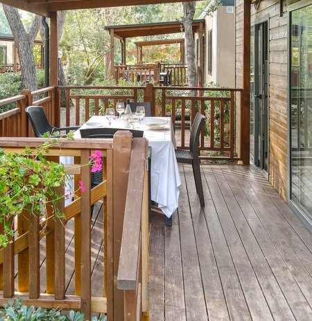 Veranda in legno apparecchiata per pranzo all'aperto.