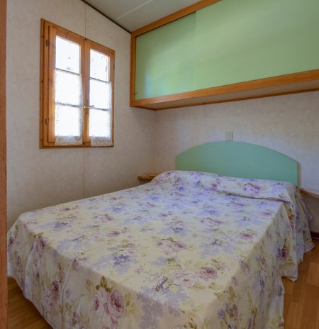 Camera con letto matrimoniale e copriletto floreale.