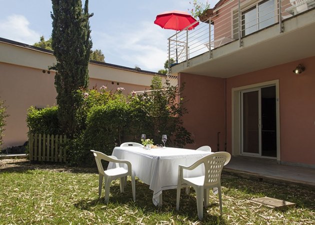 Giardino con tavolo apparecchiato e ombrellone rosso.