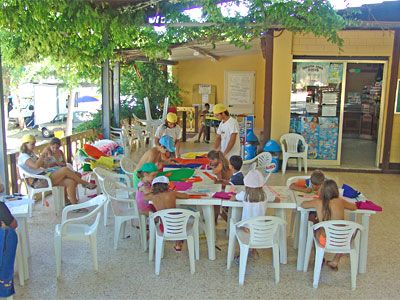 Bambini seduti a tavoli all'aperto.