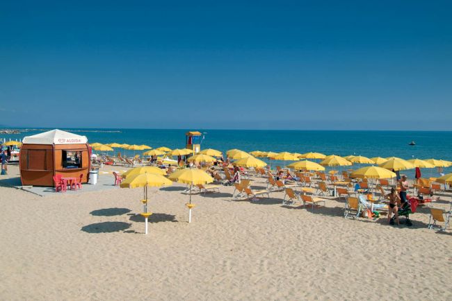Spiaggia con ombrelloni gialli e cabine.