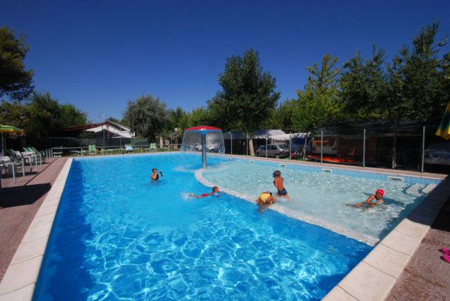 Piscina con bambini che giocano e un fungo d'acqua.