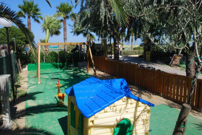 Parco giochi con casetta colorata e altalene.