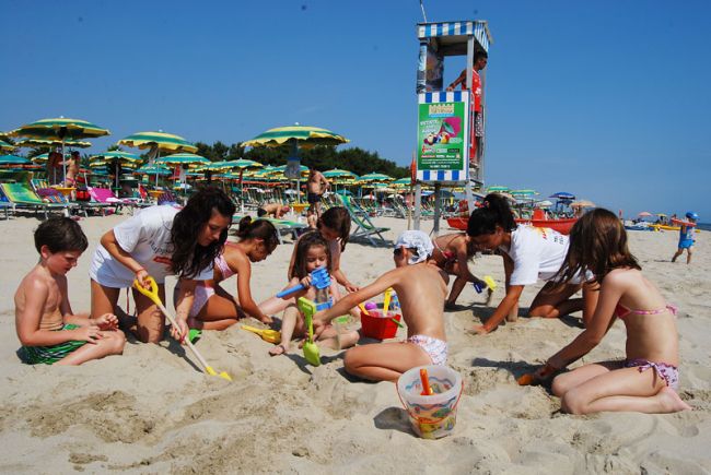 Bambini e adulti che giocano con la sabbia.