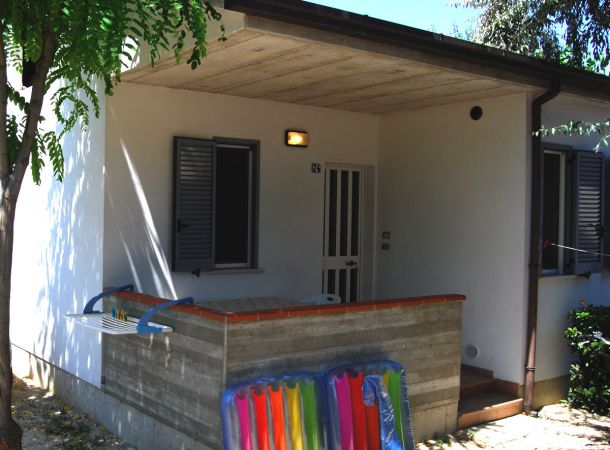 Piccolo portico con tavolo, sedie e materassino gonfiabile.