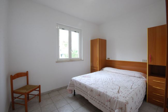 Camera con letto matrimoniale e armadio, finestra luminosa.