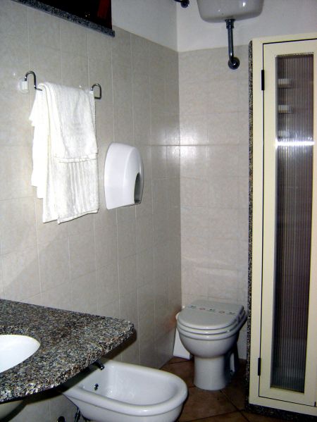 Bagno con bidet, wc, lavandino e doccia. Asciugamani appesi.