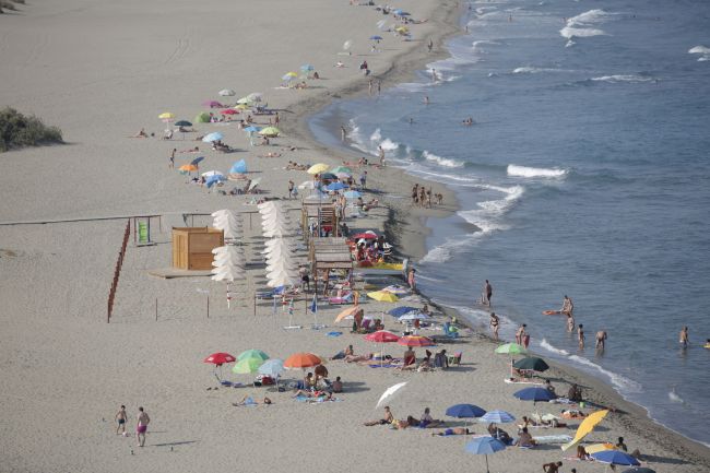 Spiaggia con ombrelloni colorati e bagnanti.