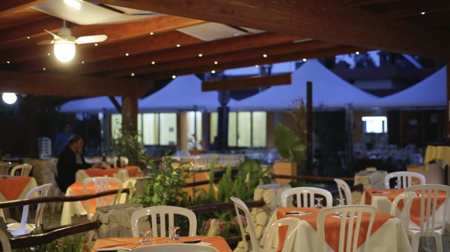 Ristorante esterno con tavoli apparecchiati di sera.