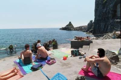 Persone su una piattaforma rocciosa vicino al mare.