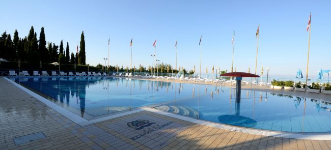 Piscina con bordo piastrellato e bandiere.