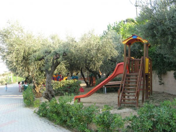 Parco giochi con scivolo tra gli alberi.