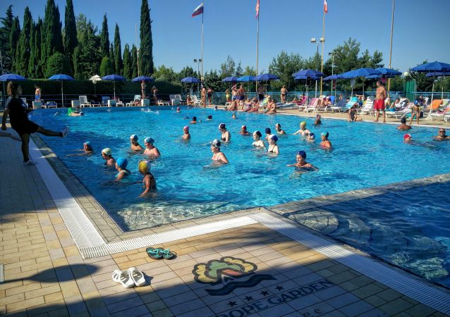 Piscina all'aperto affollata di persone che nuotano.