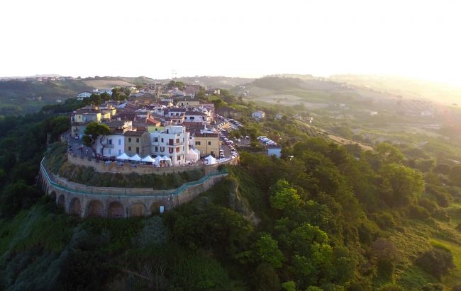 Vista aerea di un borgo in collina al tramonto.