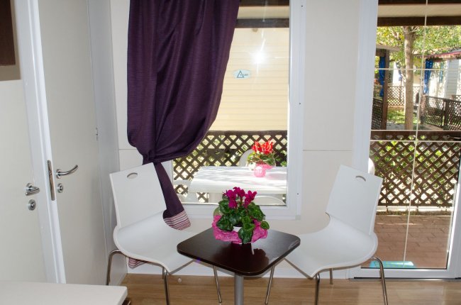 Tavolino con fiori vicino a una grande finestra e tende.