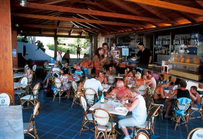 Persone sedute in un bar all'aperto sotto un tetto di legno.