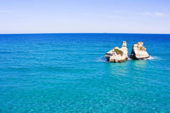 Mare azzurro con due grandi scogli al centro.