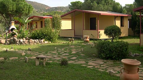 Due bungalow in un giardino con aree verdi e sentieri di pietra.