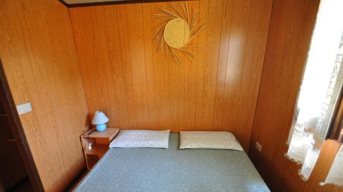Camera da letto con pannelli di legno, letto matrimoniale, lampada blu e decorazione a parete.