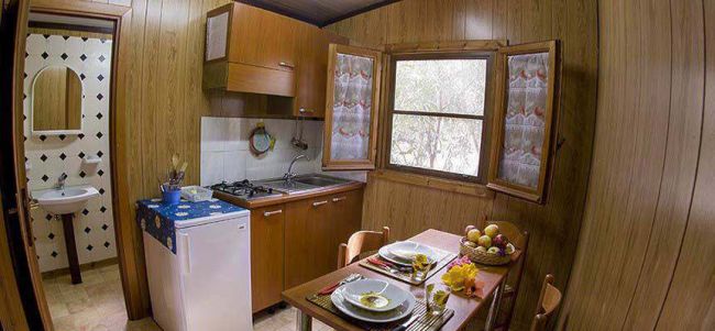 Cucina accogliente con tavola apparecchiata e finestra vista giardino.
