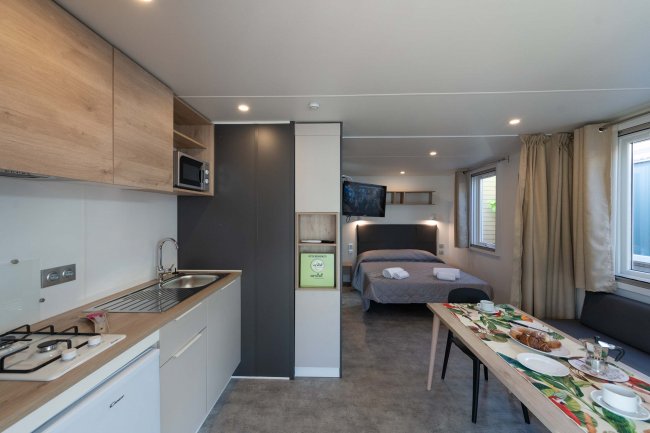 Interno di una casa mobile con cucina, tavolo e letto.