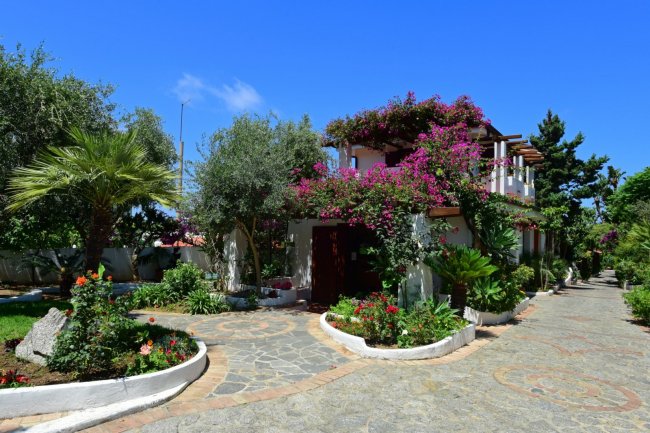 Casa con fiori rosa e giardino verde.