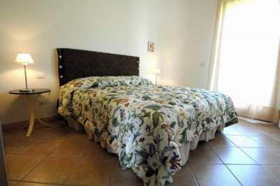 Camera con letto matrimoniale, lampade e copriletto floreale.