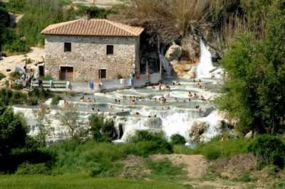 Cascate con piscine termali a terrazze e persone che nuotano.