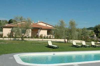 Vista di una casa con piscina e sedie a sdraio immerse nel verde.
