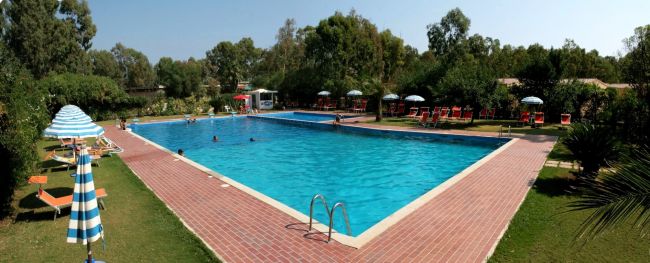 Piscina all'aperto con ombrelloni a strisce e lettini.