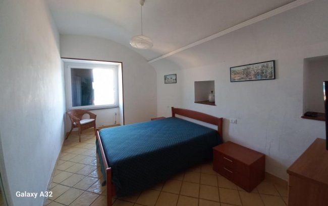 Camera da letto con letto matrimoniale e sedia vicino alla finestra.