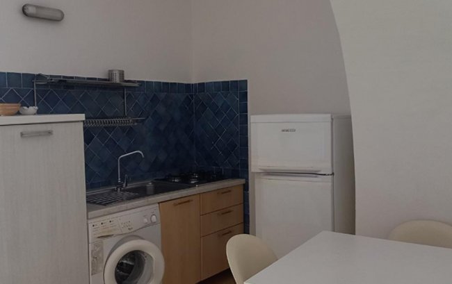 Cucina compatta con frigo e lavatrice.