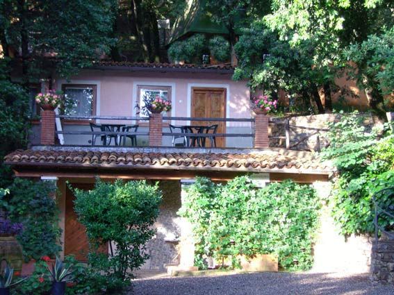 Edificio rosa con balcone e piante rampicanti.