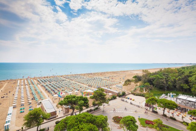 Spiaggia affollata vista dall'alto con mare e cielo.