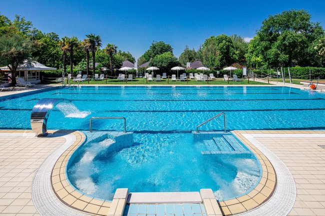 Piscina azzurra con sedie a sdraio e palme.