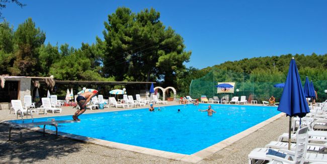 Piscina all'aperto con persone e sdraio.