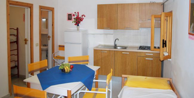 Cucina moderna con tavolo bianco, sedie gialle e un divano.