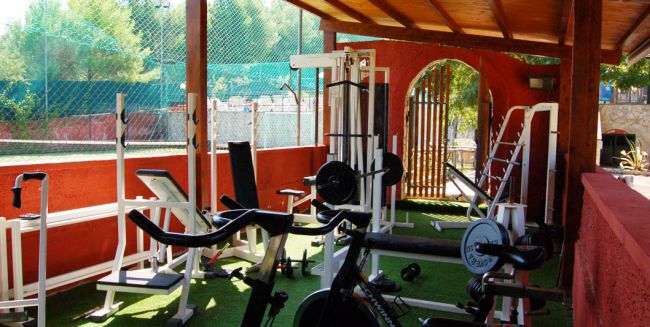 Palestra all'aperto con attrezzi da fitness sotto un tetto di legno.