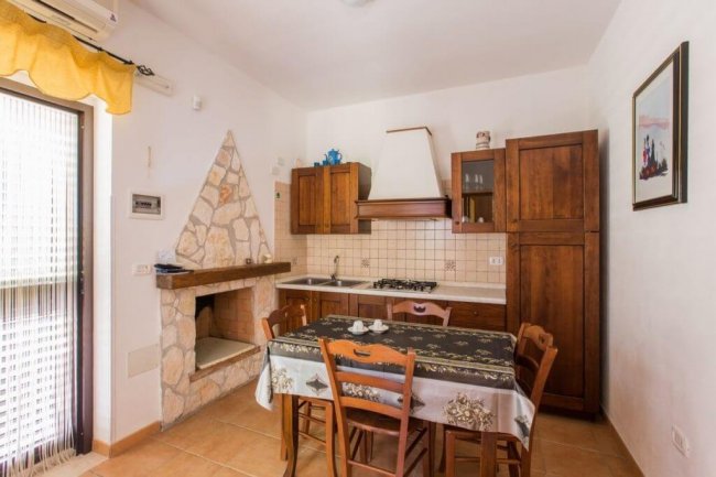 Cucina rustica con tavolo da pranzo e camino in pietra.
