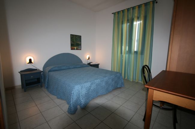 Camera con letto matrimoniale e tende a righe.