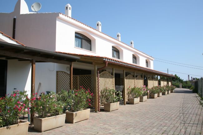 Edificio bianco con piante in vaso e patio.