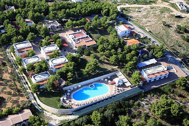 Vista aerea di un complesso turistico con piscina e edifici circondati da alberi.