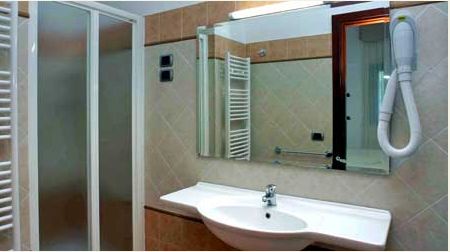 Bagno moderno con doccia, specchio e asciugacapelli a muro.