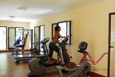 Due persone utilizzano attrezzi da palestra in una sala luminosa.